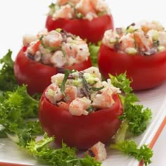 four tomatoes with shrimp salad in them on a white plate