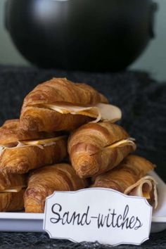 some croissants are piled on top of each other with a sign that says sand - witches