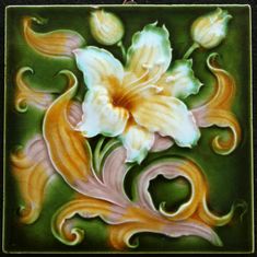 a ceramic tile with flowers and swirls painted on it