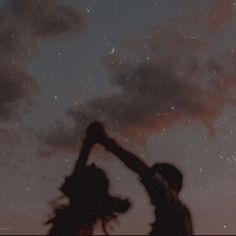 two people reaching up into the sky at night