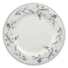 a white plate with blue and purple flowers on it's rim, against a white background