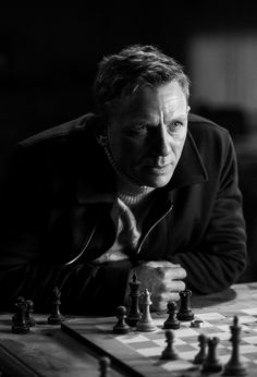 a man sitting at a chess board with his hand on the queen's pawn