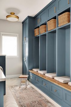 a bathroom with blue cabinets and baskets on the shelves, along with an area rug