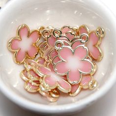 Qty x 1 Charm Light gold plated flower charms with pink and white translucent enamel as pictured.  Approximate Measurements: 18mm x 15mm x 1.2mm with a 2mm hole Pink Enamel Jewelry With Flower Charm, Pink Enamel Charms Jewelry, Pink Enamel Flower-shaped Jewelry, Pink Enamel Jewelry With Charms, Pink Enamel Charms For Gifts, Cute Pink Flower Pendant Jewelry, Nickel-free Pink Flower-shaped Jewelry, Gold Jewelry With 3d Flowers For Jewelry Making, Pink Flower Pendant Jewelry With Charms