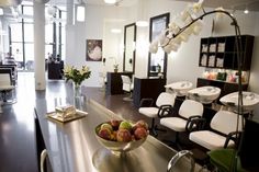 a bowl of fruit sitting on top of a counter next to chairs in a salon