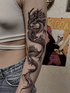 a woman's arm with a dragon tattoo on the left side of her body