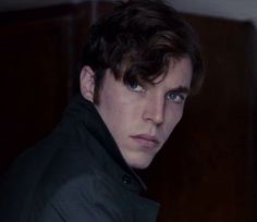 a young man with blue eyes is looking at the camera while wearing a black jacket