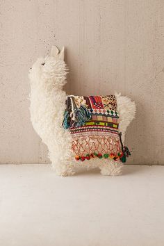 a white llama stuffed animal sitting next to a wall