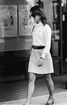 black and white photograph of woman walking on sidewalk