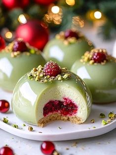 three desserts with raspberry filling on a plate next to a christmas tree