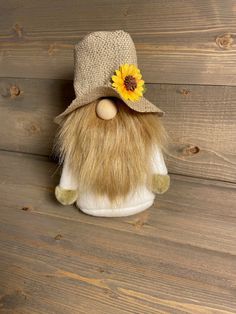 a stuffed animal with a hat and sunflower on it's head sitting on a wooden surface