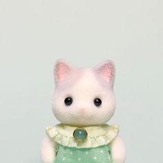 a small white cat wearing a green dress