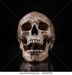 a human skull on a black background with reflection in the floor and one eye open