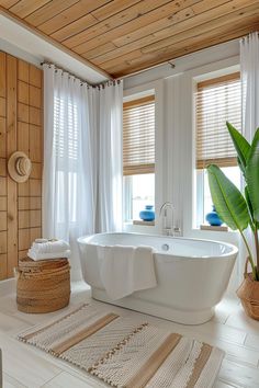 a large white bath tub sitting in a bathroom next to two windows with wooden shutters