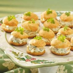 there are many small sandwiches on the plate with green garnishes and parsley