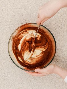 someone is mixing something in a glass bowl