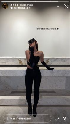 a woman in black catsuits standing next to a marble counter with her hands on her face