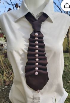 a man wearing a tie with pearls on it's side and buttons down the middle