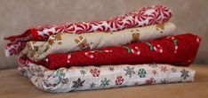 four different colored fabric wrapped in christmas wrappings sitting on a wooden table next to each other