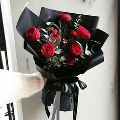 a person holding a bouquet of red roses