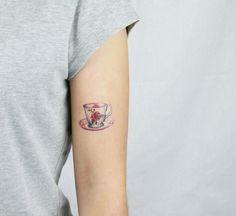 a woman with a tattoo on her arm holding a cup and saucer in one hand