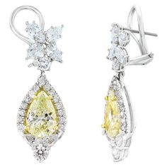 A beautiful and chic pair of drop earrings showcasing a cluster of brilliant mixed-cut diamonds, and pear-shaped brilliant yellow diamonds set in an intricate and stylish design. 10 Mixed cut Diamonds weigh 1.91 carats in total. 2 yellow diamonds weigh 2.89 carats in total. They are made in 18k white gold. 44 accent diamonds weigh 0.83 carats in total. The color of these gemstones is ideal, with great luster/shine. Omega clasp with a post. Fine Jewelry Yellow Diamond Wedding Earrings, Luxury Pear-shaped Yellow Gold Diamond Earrings, Luxury Yellow Pear-shaped Jewelry, Yellow Pear-shaped Jewelry With Diamond Accents, Elegant Yellow Diamond-cut Earrings, Fancy Yellow Diamond, Pear Diamond, Diamond Drop Earrings, Diamond Drops