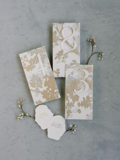 wedding stationery with gold foil flowers and monogrammed cards on grey background, top view