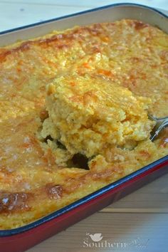 cheese grits casserole in a red baking dish with a spoon scooping out