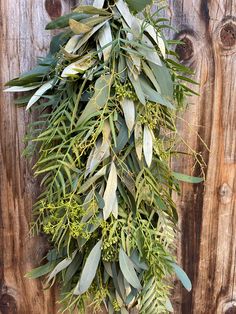 a bunch of green leaves hanging from the side of a wooden wall