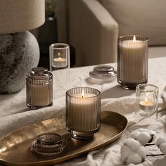 three candles are on a tray with cotton balls and other items in front of them