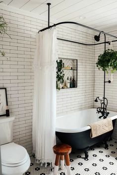 a black and white bathroom with a tub, shower curtain, toilet and stool in it