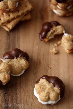 chocolate covered cookies and marshmallows are on a wooden table next to crackers