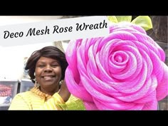 a woman holding a large pink rose in front of a sign that says deco mesh rose wreath