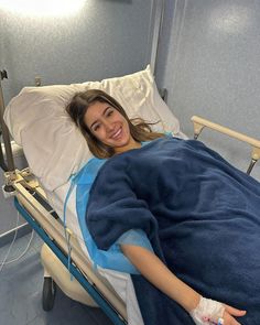 a woman laying in a hospital bed with an oxygen tube attached to her arm and smiling at the camera