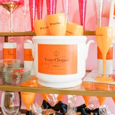 an orange and white bucket filled with wine glasses on top of a shelf in a store