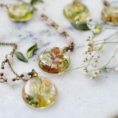 several necklaces with flowers and leaves are on a table next to other jewelry items