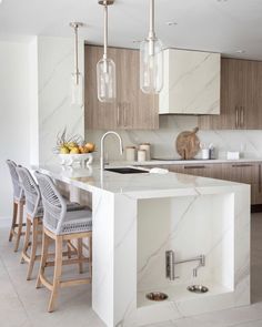 a kitchen with white marble counter tops and wooden cabinets, along with gray bar stools