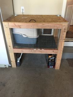 a wooden table sitting on top of a floor next to a white refrigerator freezer