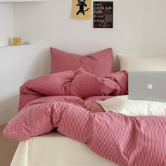 a laptop computer sitting on top of a bed covered in red and white striped sheets