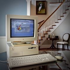 an old computer sitting on top of a glass table in front of a stair case