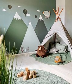 a child's bedroom with a teepee tent and mountains painted on the wall