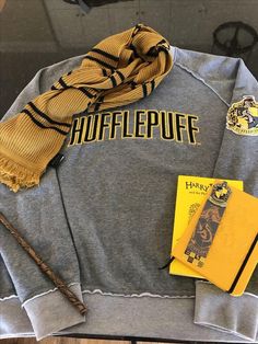 a harry potter sweatshirt, scarf and book are on display in a shop window at hogwarts