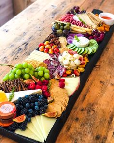 a platter filled with cheese, fruit and crackers on top of a wooden table