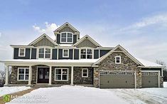 a large house with two garages and snow on the ground in front of it