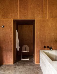 a bathroom with wooden walls and flooring next to a white chair in the middle