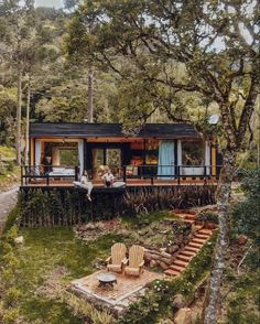 two people are sitting on the deck of a house in the middle of the woods