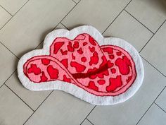 a red and white heart shaped animal print hat on the floor next to a tiled floor