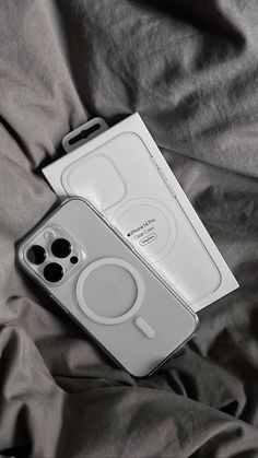 an iphone case sitting on top of a bed next to a box with two buttons