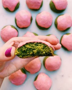 a hand holding a green and pink doughnut