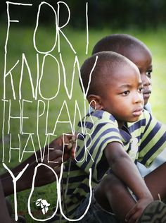 two young boys sitting on the grass and one is holding his arm around the other